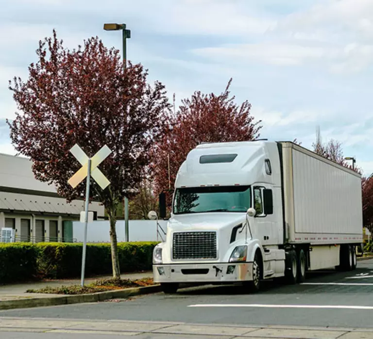 White semi-truck stopped at a railroad crossing